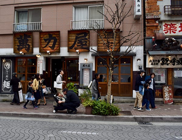 Exterior shot at Man Riki Ya Noodle shop with lots of people Azabujuban Tokyo Japan